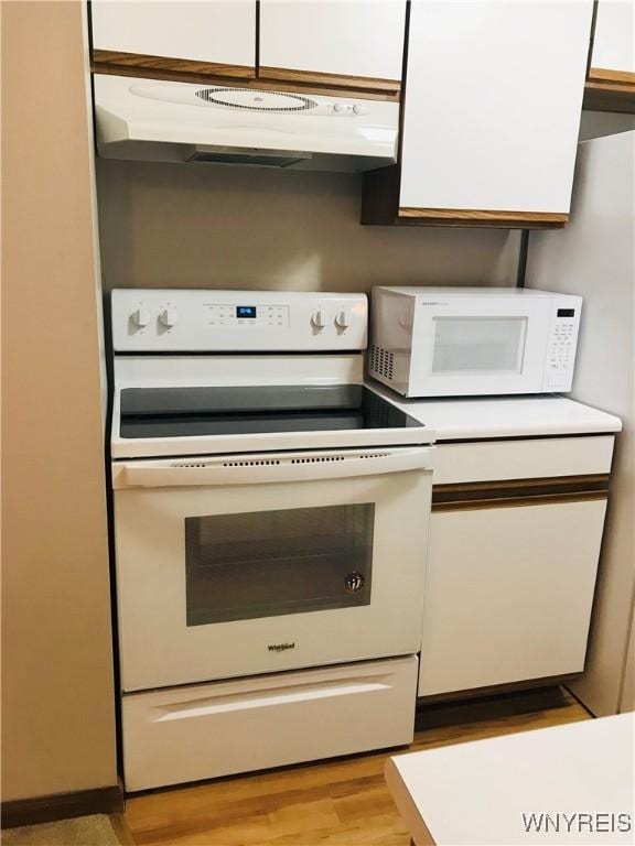 kitchen with under cabinet range hood, white cabinets, white appliances, and light countertops