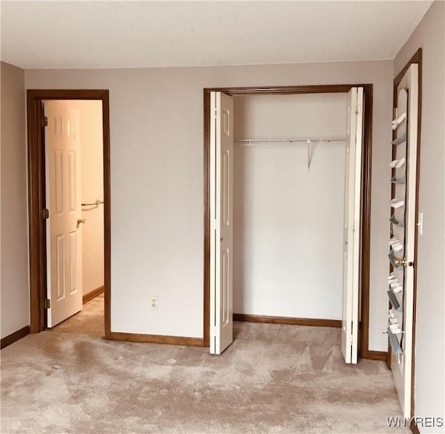 unfurnished bedroom with baseboards, a closet, and light carpet