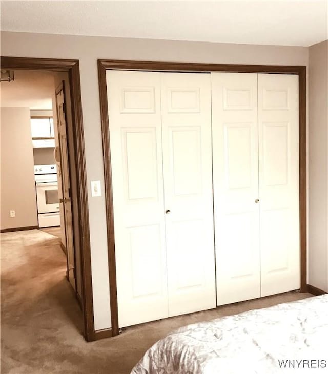 bedroom with a closet, light carpet, and baseboards