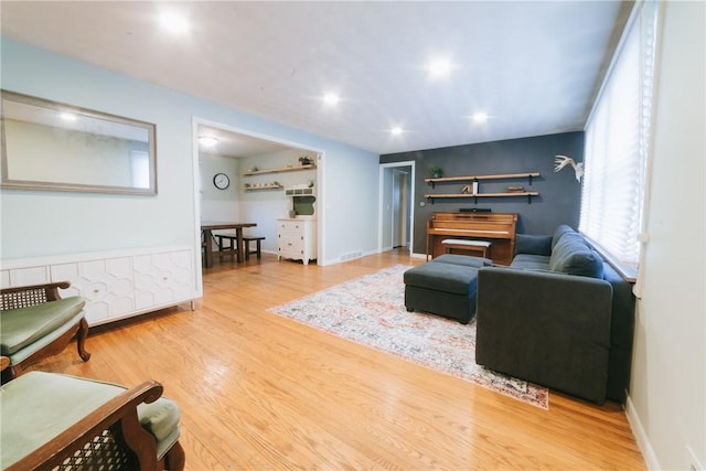 living area with recessed lighting, wood finished floors, visible vents, and baseboards