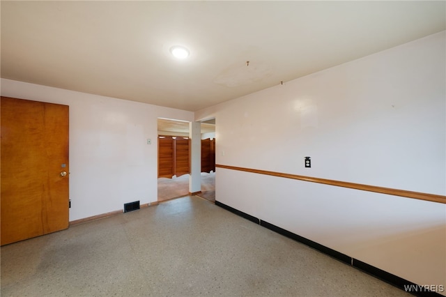 spare room with visible vents, speckled floor, and baseboards