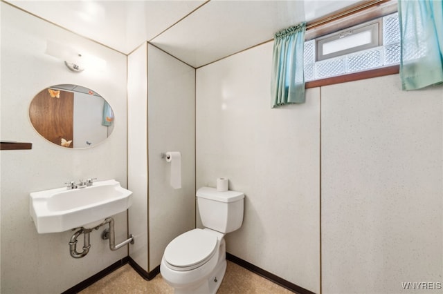 bathroom with toilet, baseboards, and a sink