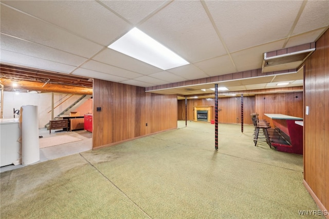 finished basement with a drop ceiling, washer / dryer, and wood walls