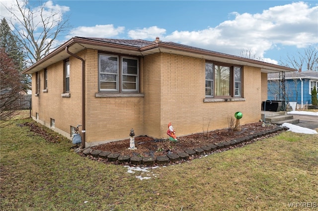 view of home's exterior featuring brick siding and a lawn