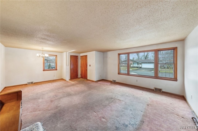 spare room with a chandelier, plenty of natural light, and visible vents