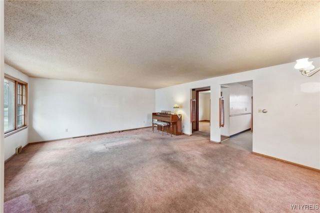 unfurnished room with light colored carpet, baseboards, a chandelier, and a textured ceiling