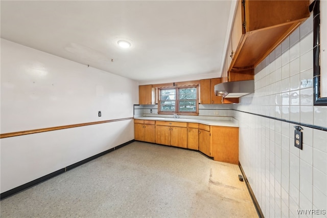 kitchen featuring light countertops, baseboards, brown cabinets, and a sink