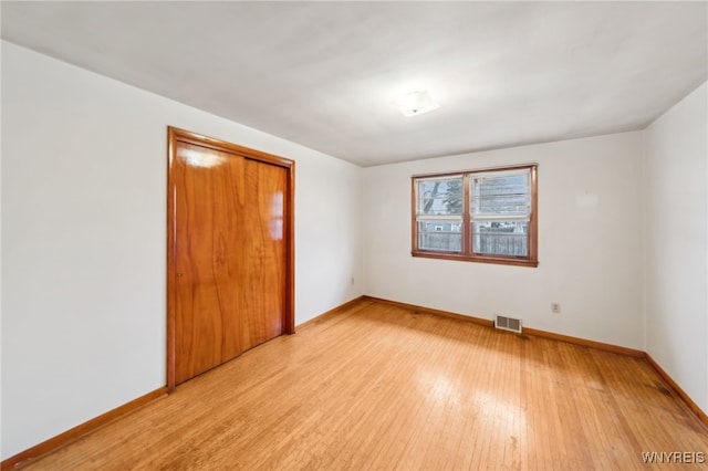 spare room featuring light wood-type flooring, baseboards, and visible vents