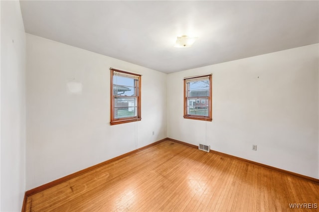 spare room featuring visible vents, baseboards, and light wood finished floors