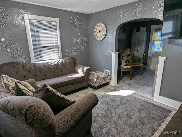 living room with wood finished floors, arched walkways, and baseboards