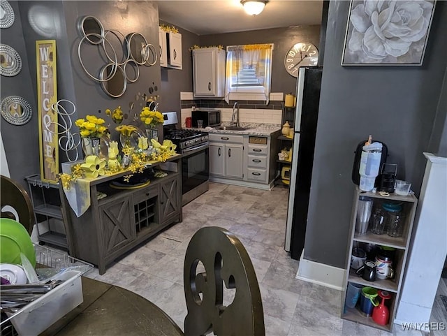 kitchen with a sink, light countertops, white cabinets, appliances with stainless steel finishes, and tasteful backsplash