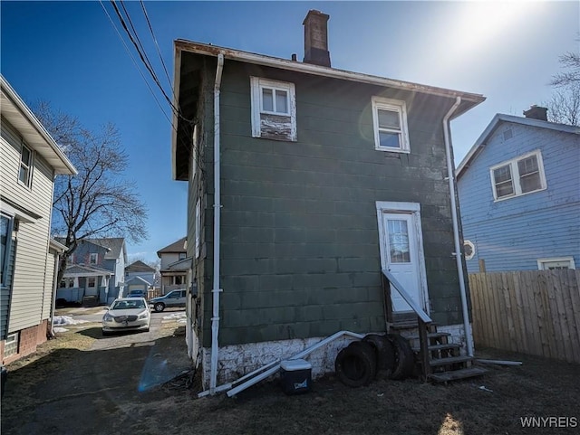 back of property with entry steps, a chimney, and fence