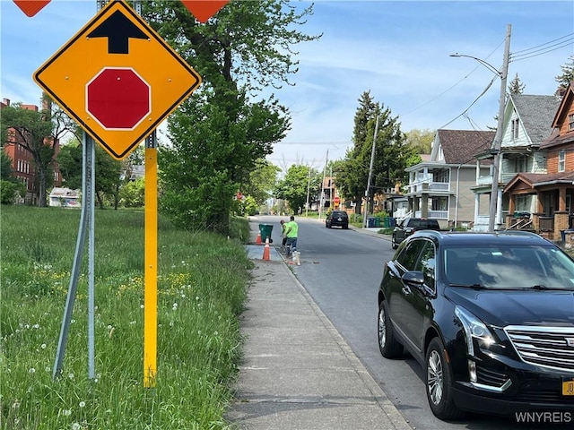 view of road with traffic signs, a residential view, sidewalks, and street lighting