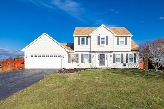 colonial house with aphalt driveway, a front yard, an attached garage, and fence