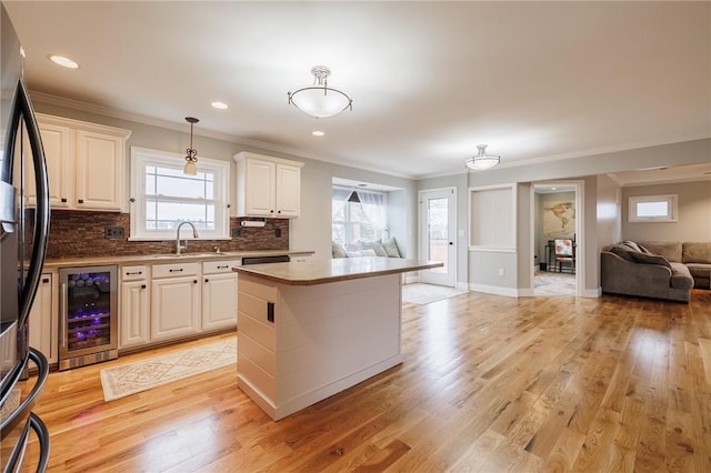 kitchen with open floor plan, beverage cooler, black refrigerator with ice dispenser, and light wood finished floors