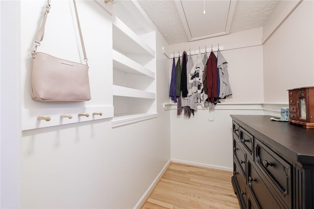 walk in closet featuring light wood-style flooring and attic access