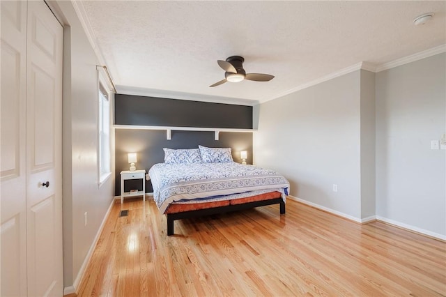 bedroom with a textured ceiling, light wood-style flooring, baseboards, and ornamental molding