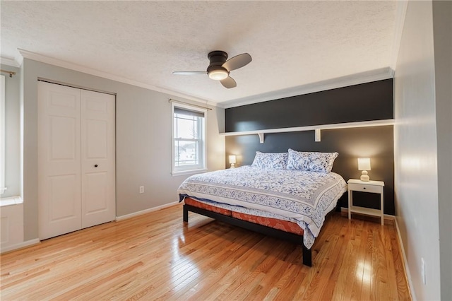 bedroom featuring ornamental molding, baseboards, light wood finished floors, and a textured ceiling