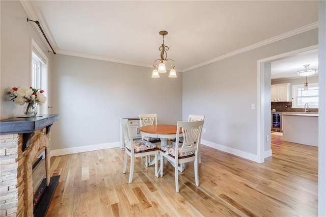 dining room with light wood finished floors, an inviting chandelier, baseboards, and ornamental molding