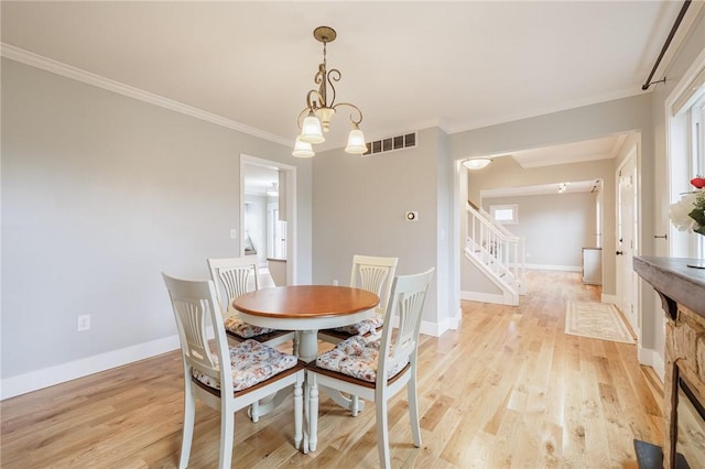 dining space featuring visible vents, crown molding, stairs, and light wood finished floors