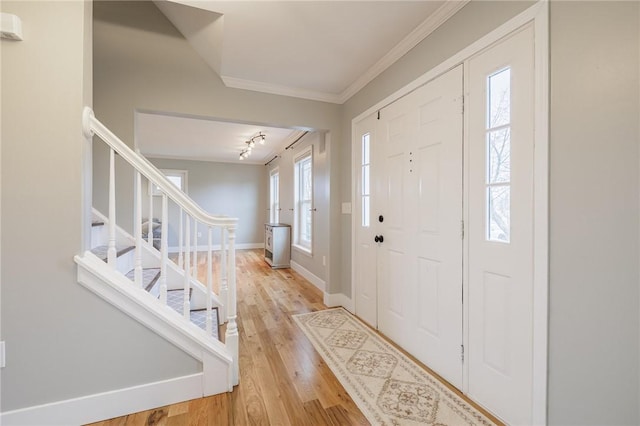 entryway featuring light wood-style flooring, stairs, baseboards, and ornamental molding