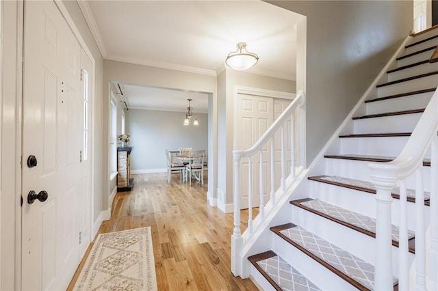 stairway with crown molding, wood finished floors, and baseboards