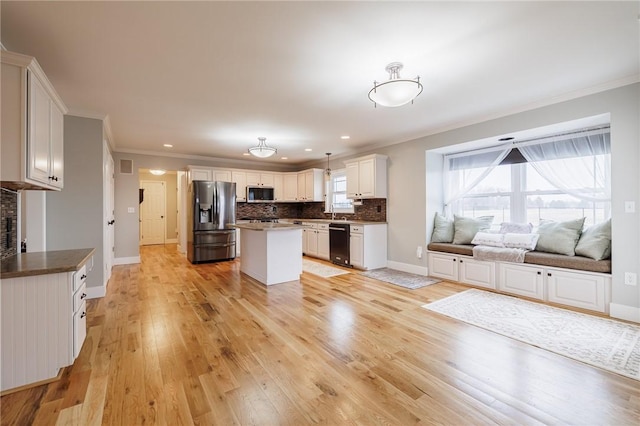 kitchen with tasteful backsplash, appliances with stainless steel finishes, crown molding, and light wood-style floors