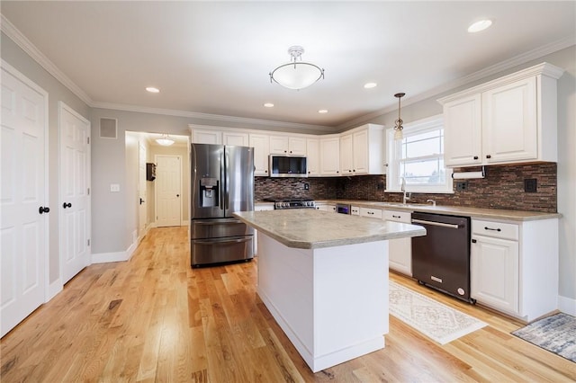 kitchen with a sink, stainless steel appliances, light wood-style flooring, and white cabinetry