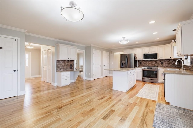 kitchen featuring light wood finished floors, a center island, stainless steel appliances, white cabinetry, and a sink