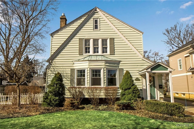 view of front of property featuring a chimney, a front lawn, and fence