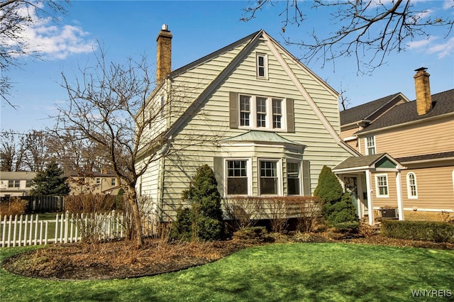 back of property with central air condition unit, fence, a lawn, and a chimney