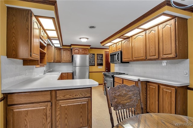 kitchen featuring light floors, a peninsula, a sink, light countertops, and appliances with stainless steel finishes