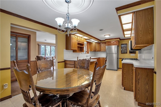 dining area featuring a chandelier, light floors, and ornamental molding