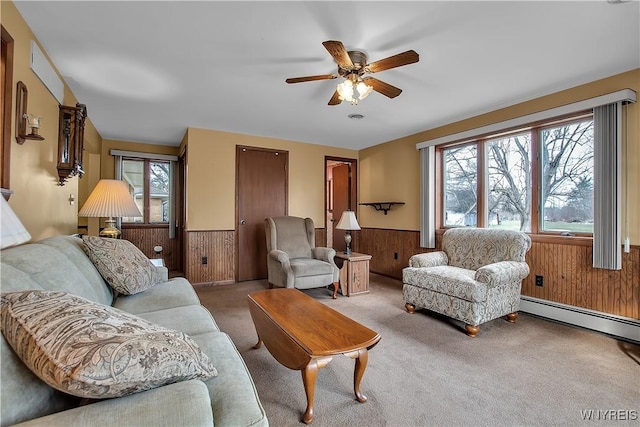 carpeted living room with wooden walls, wainscoting, and a baseboard heating unit