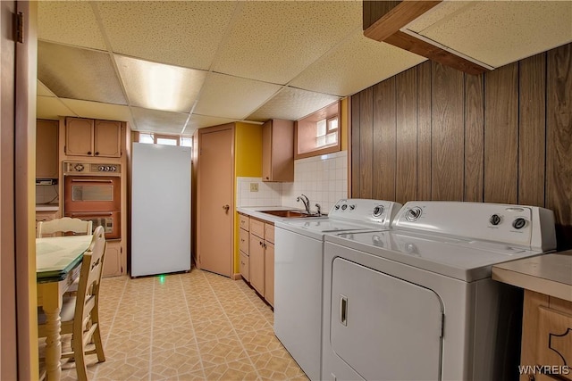 laundry room with independent washer and dryer, wood walls, and a sink