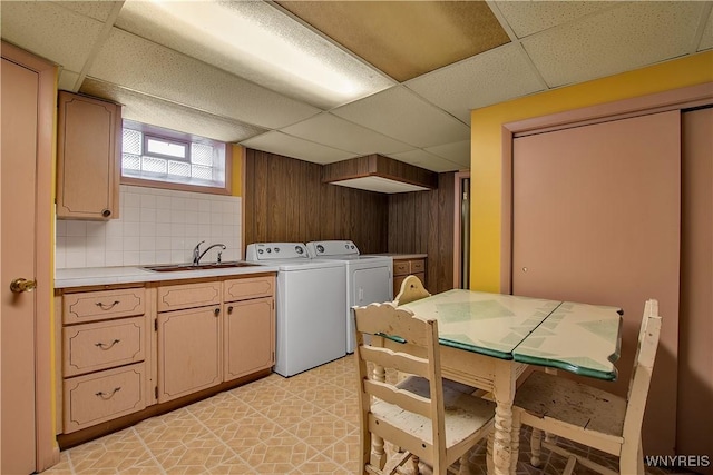 clothes washing area featuring a sink, cabinet space, wooden walls, and washing machine and dryer