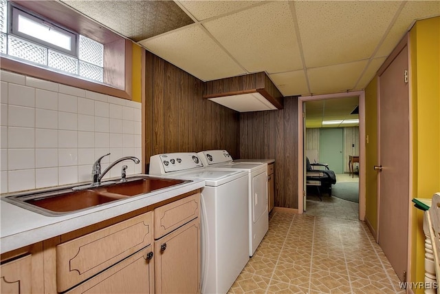 laundry room featuring a sink, cabinet space, washing machine and dryer, and wood walls