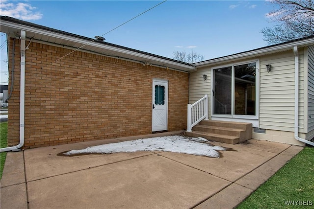 back of property featuring a patio, brick siding, and crawl space