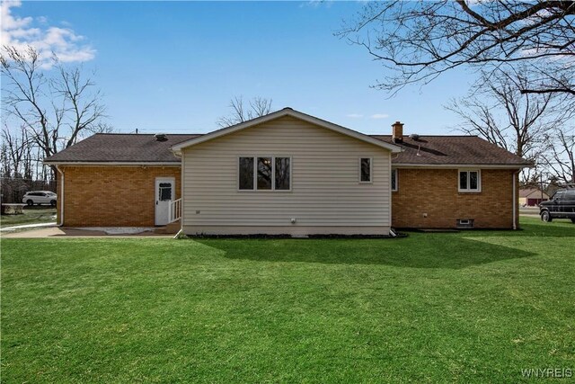 rear view of property featuring a yard, brick siding, and a chimney