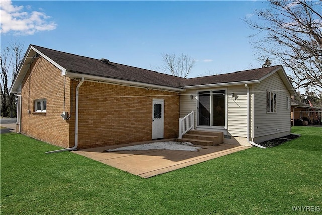 rear view of property featuring roof with shingles, brick siding, entry steps, a patio area, and a lawn