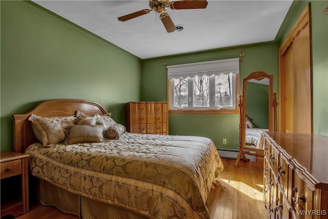 bedroom featuring wood finished floors, a ceiling fan, and a baseboard radiator