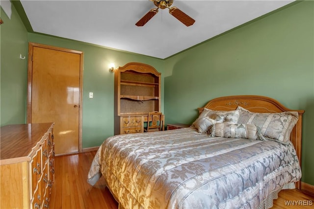 bedroom featuring a ceiling fan, baseboards, and wood finished floors