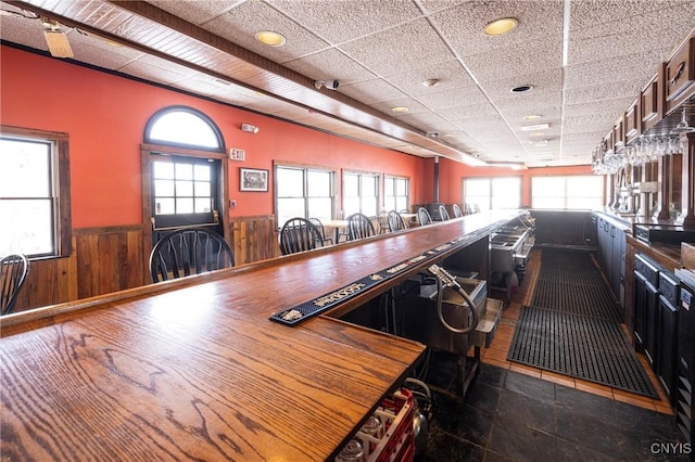 interior space featuring a paneled ceiling, a wainscoted wall, a wealth of natural light, and wood walls