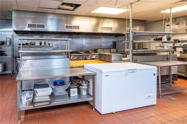 kitchen with tile patterned flooring, refrigerator, visible vents, and a drop ceiling