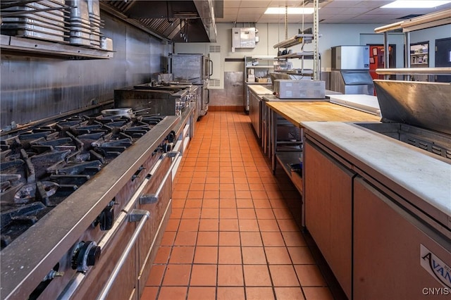 kitchen with light tile patterned floors, a paneled ceiling, high end stainless steel range oven, and open shelves