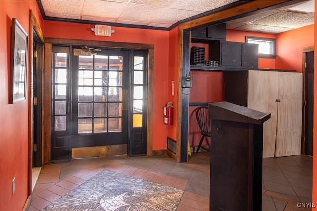 doorway to outside with tile patterned flooring, a paneled ceiling, and baseboards