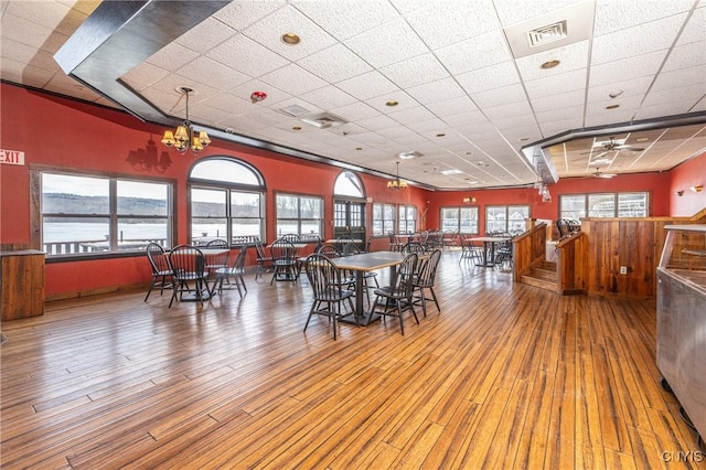 dining space featuring a paneled ceiling, visible vents, wood-type flooring, and an inviting chandelier