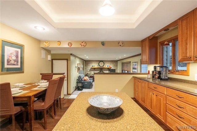 kitchen with a tray ceiling, recessed lighting, wood finished floors, and brown cabinets