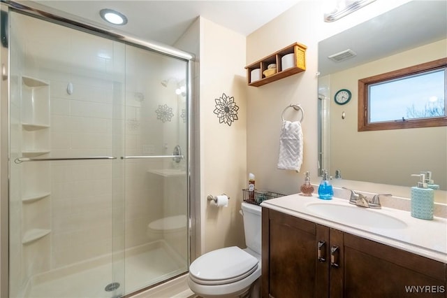 full bathroom with vanity, a shower stall, toilet, and visible vents