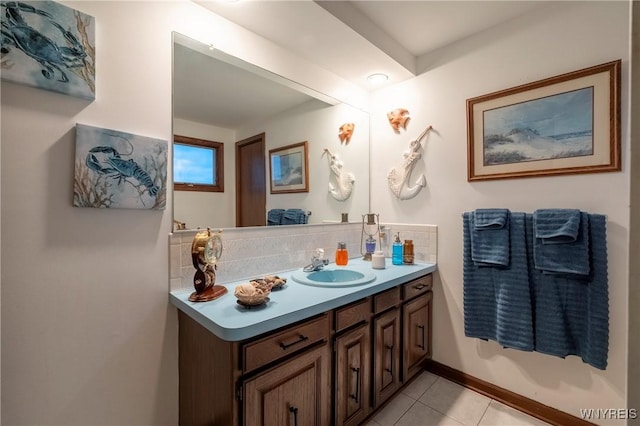 bathroom featuring tile patterned flooring, vanity, baseboards, and backsplash